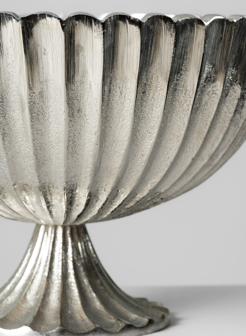 Close-up of the 12in Palermo Brushed Silver Scallop Compote Metal Bowl, featuring a fluted design and scalloped edge on a matching pedestal base, set against a plain light background.