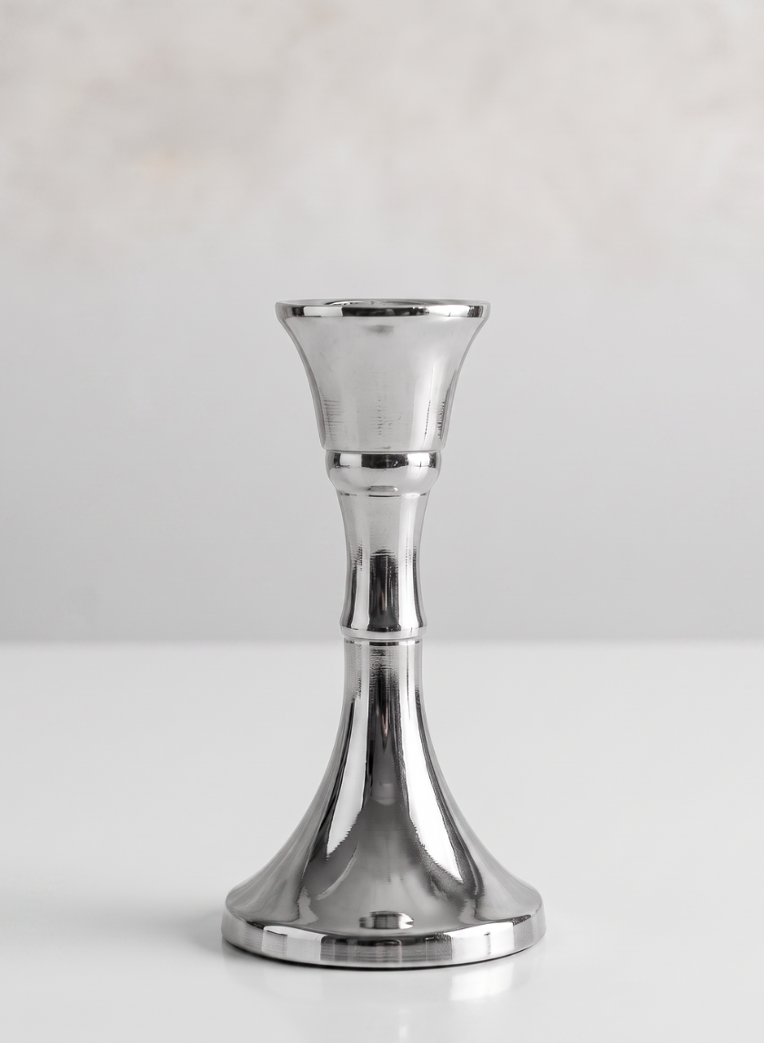 A single 4.5in tall silver metal candlestick stands upright on a white surface with a plain light background.