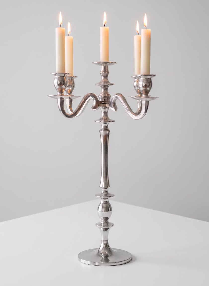 A 25.75in Tall Silver Metal Candelabra with five lit cream-colored candles stands on a white surface against a plain light gray background.