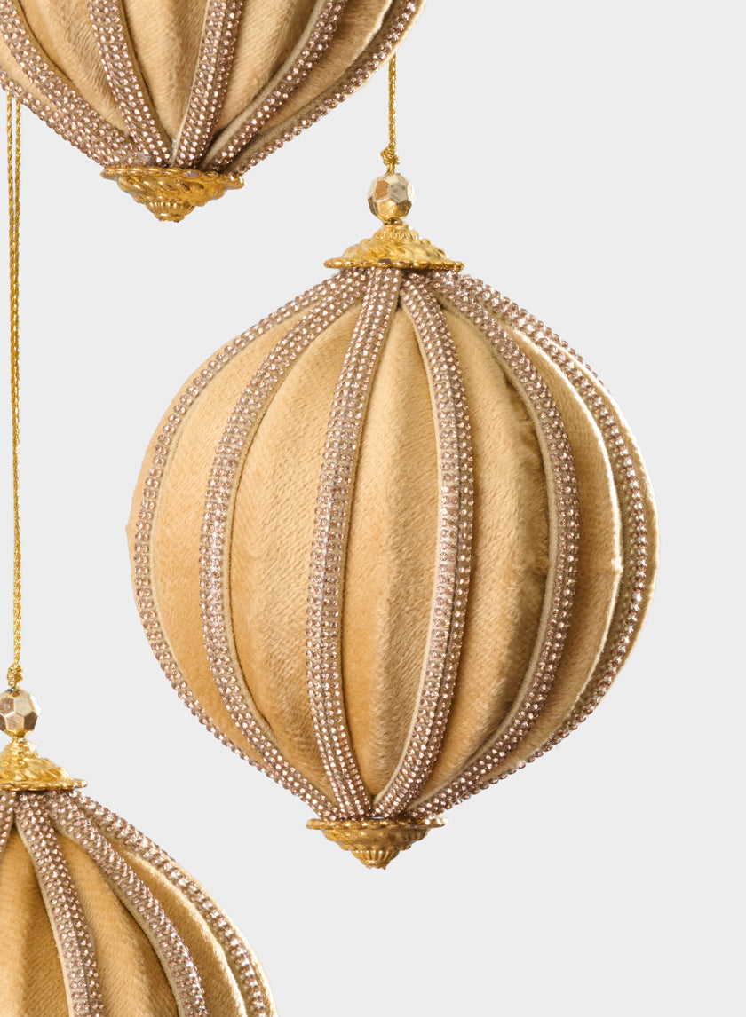 A 4-inch round gold velvet and rhinestone decorative hanging ball ornament is showcased in the center, partially framed by other beaded gold and beige ornaments against a light background.