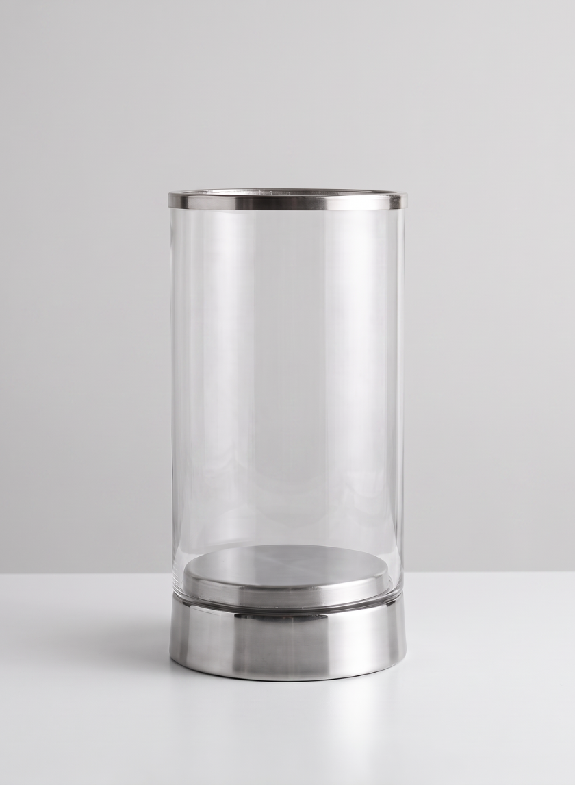 An 11.5in Tall Silver & Glass Candle Hurricane, featuring a clear cylindrical glass body with a silver metal base and rim, is placed on a white surface against a light gray background.