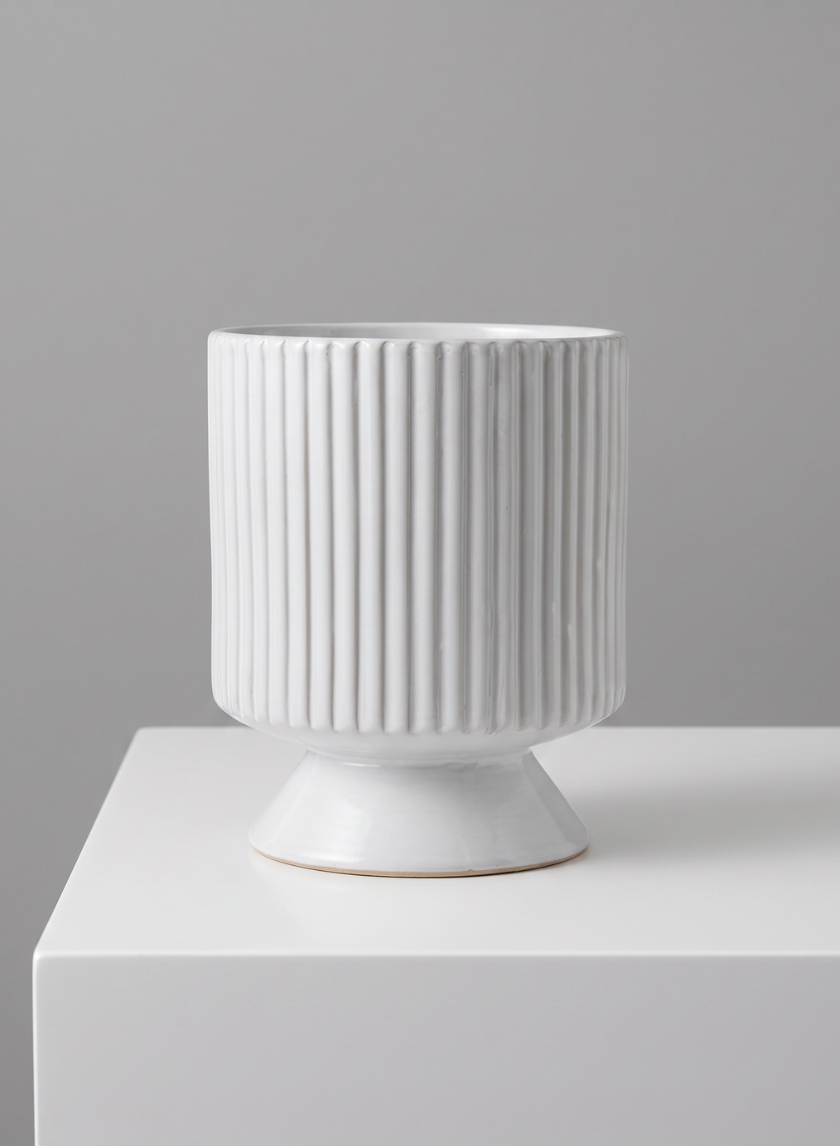 The 8in Tall Florist Choice White Cachepot with Base, featuring vertical ridges, stands on a matching white pedestal against a plain gray background.