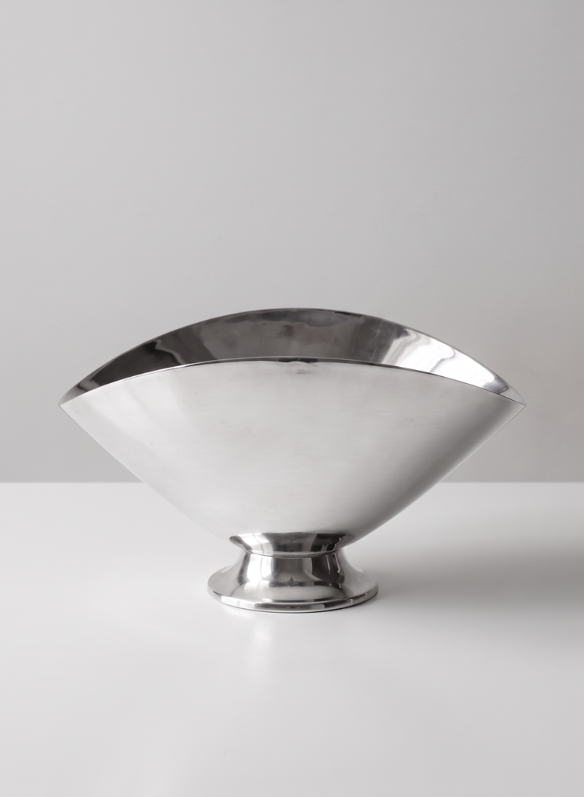 A 6.5in Wide Nickel Oval Bowl with a polished metallic finish and a wide, curved rim sits empty on a white surface against a plain, light gray background.