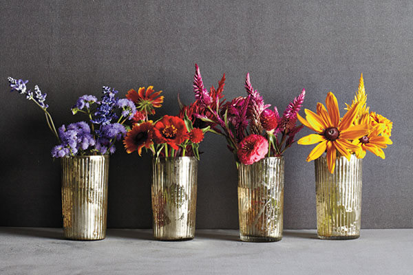 store-bought flowers rearranged by color in small mercury glass containers