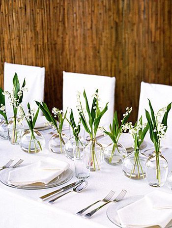 tablescape with lily of the valley in clear ball bud vases down the center of a long table