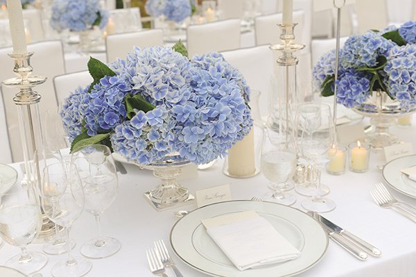 classic wedding reception tables with silver candlesticks and silver urns with blue hydrangea bouquets