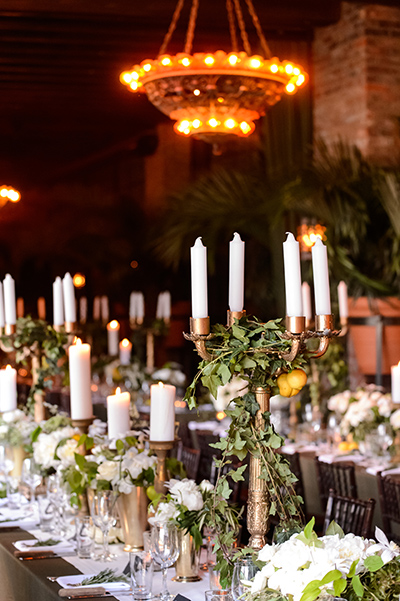 Long tables with antique gold pillar holders, candelabras, and brass julep cups.