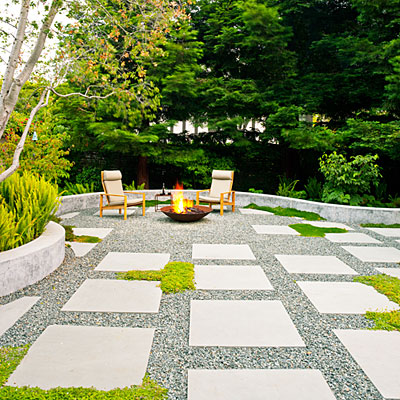 patio of bluestone pavers, crushed rock, and low groundcovers, edged with a sinuous concrete seat wall, adds a touch of cozy with a contained fire burning in a custom firepit of Cor-ten steel.
