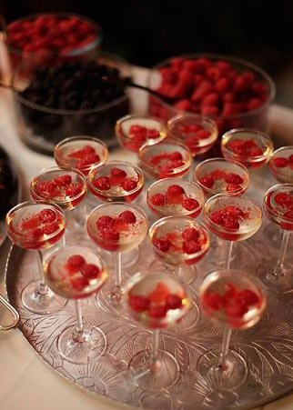 champagne coupes with red raspberries on silver tray
