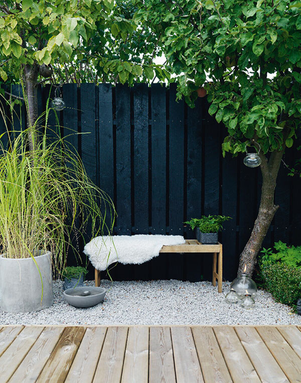 small garden with black wall fence bench and gray planters