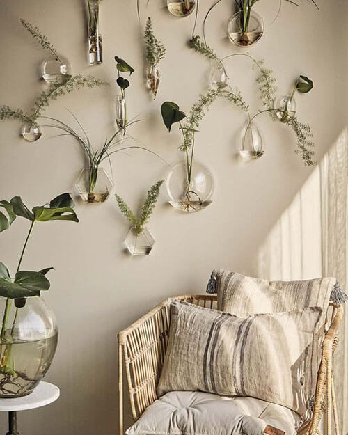 cream color wall with wall vases with plants and wicker chair with neutral pillows