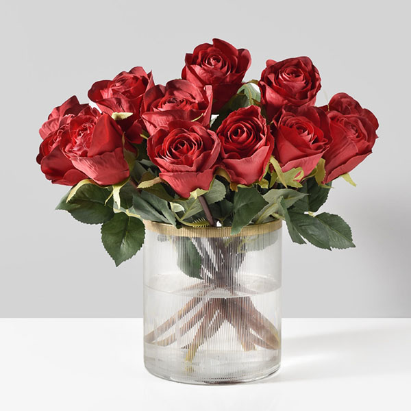 red silk roses in clear glass vase with gold rim