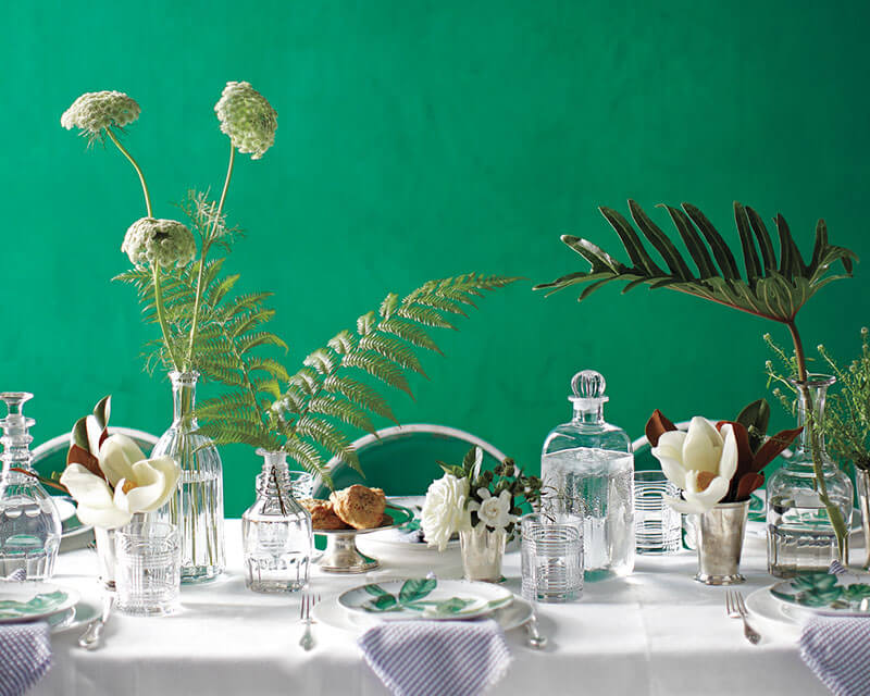 tablescape with  Queens Anne's lace ferns and greenery in bud vases and magnolia flowers in julep cups