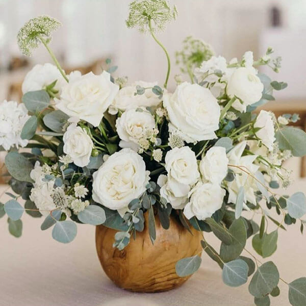 white roses with silver dollar eucalyptus and Queen Anne's lace in wood fishbowl vase