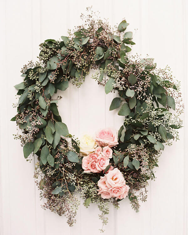 seeded eucalyptus wreath with clusters of pink roses at the bottom