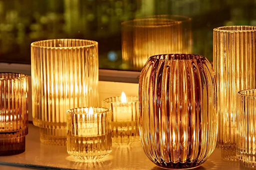 A collection of glass vases with lit candles arranged neatly on a window sill.
