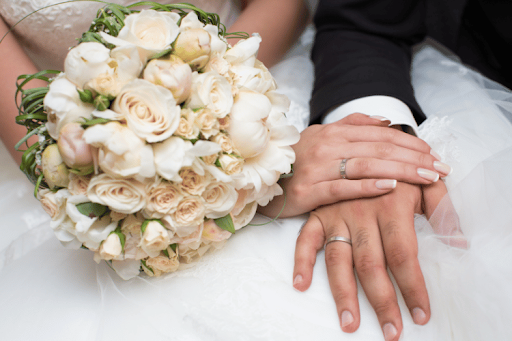 Wedding couple hands with bouquet and rings.