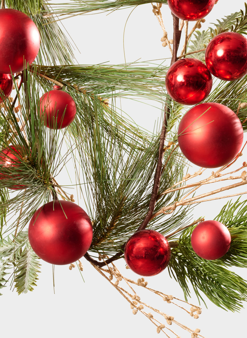 The 60in Long Classic Pine Garland with Red Ornaments &amp; Glitter Berries features red ornaments hanging among lush green pine branches, accented with glittering berries, all set against a white background.