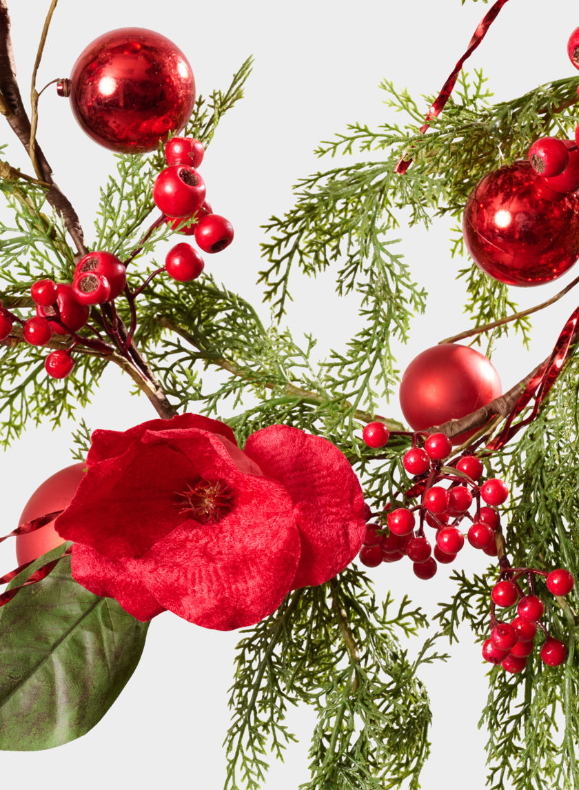 The 5ft Red Magnolia and Ball Pine Garland features vibrant red berries, a bold red magnolia flower, green pine branches, and shiny red ornaments for a festive holiday arrangement set against a plain white background.