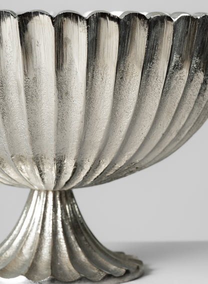 Close-up of the 12in Palermo Brushed Silver Scallop Compote Metal Bowl, featuring a fluted design and scalloped edge on a matching pedestal base, set against a plain light background.