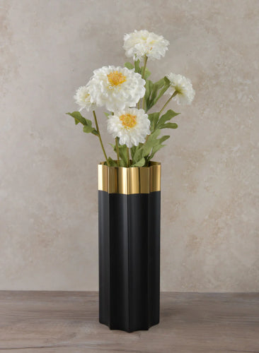 Black and gold vase with white flowers on a neutral background