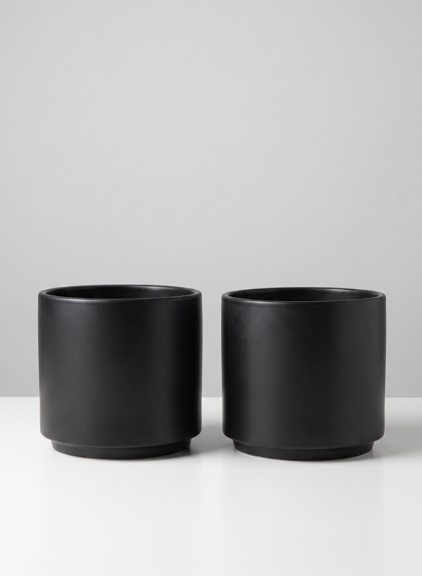 Two identical 5.25in Tall Florist Choice Matte Black Cylinder pots, sold as a set of 2, are placed side by side on a white surface against a light gray background.