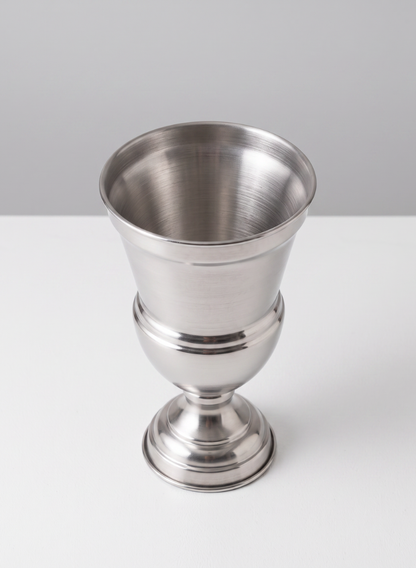 A shiny, empty 11.25in tall silver urn metal vase sits on a white surface with a light gray background.