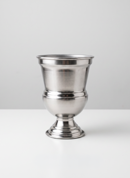 A 7.5in Tall Silver Urn Metal Vase rests on a white surface against a plain light gray background.