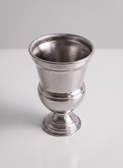 The 7.5in Tall Silver Urn Metal Vase, featuring a wide rim and a rounded base, sits on a white surface against a light gray background.