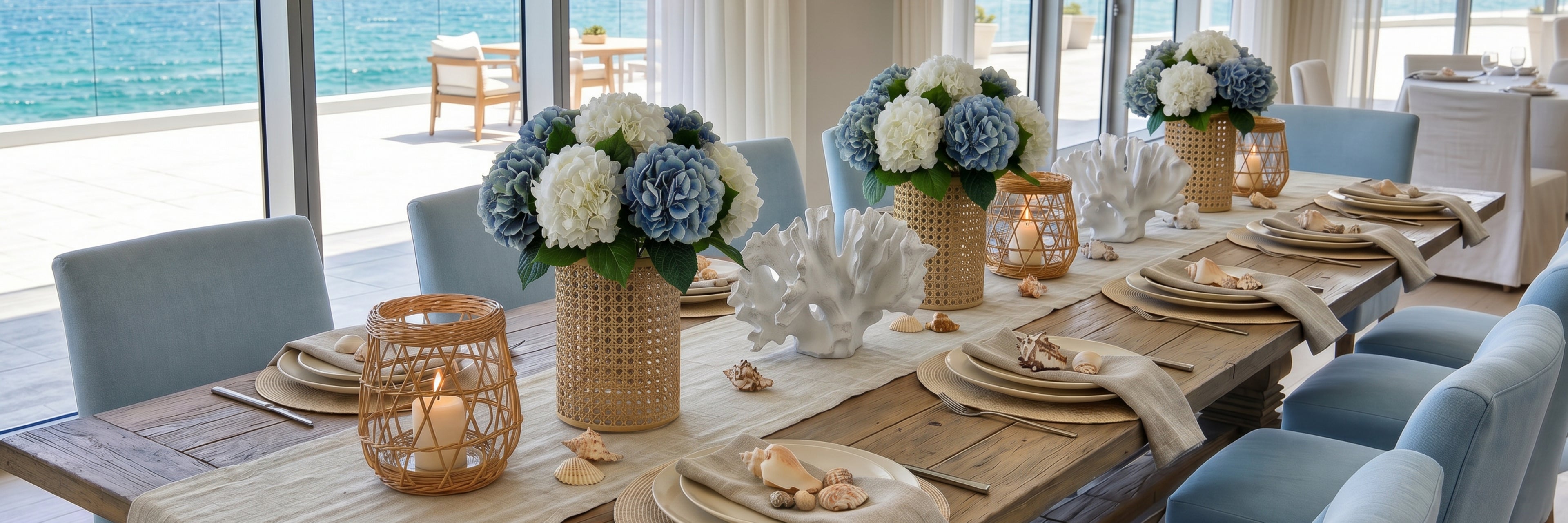 Dining table set with floral arrangements, candles, and plates in a beachside dining area.