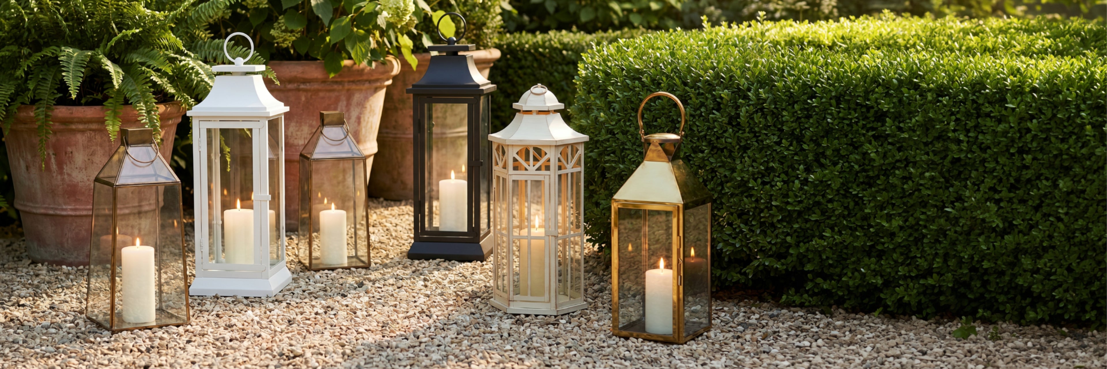 Decorative lanterns with candles on a pebble path in a garden setting