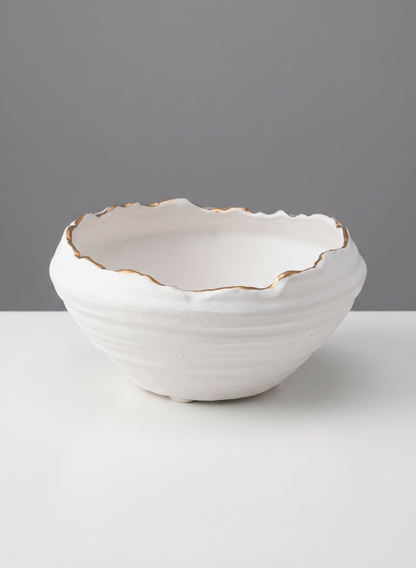 A 6in Clay White Porcelain Bowl with Gold Edging, featuring an uneven, wavy rim highlighted by a delicate gold edge, sits on a white surface against a plain gray background.