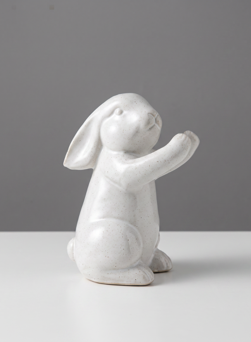 A set of four 6.5-inch tall aged white porcelain rabbits with speckled details sit upright on a white surface against a plain gray background.