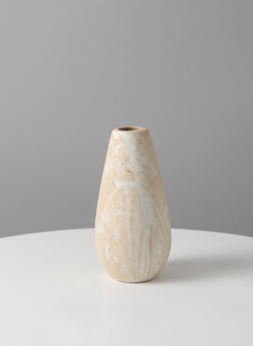 A 5in tall "Travertine Look" ceramic bud vase with a beige marbled finish and a narrow opening sits on a white round table against a plain gray background.