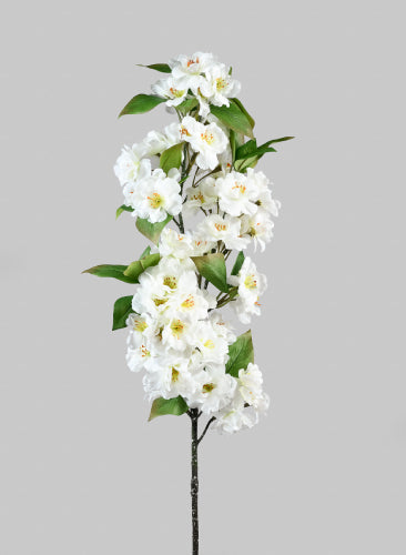 Artificial white flower branch with green leaves on a gray background