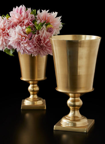 Two gold vases with a bouquet of pink flowers on a black background