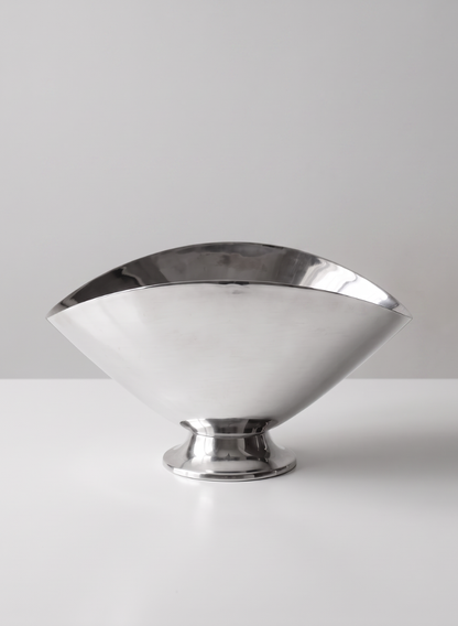A 6.5in Wide Nickel Oval Bowl with a polished metallic finish and a wide, curved rim sits empty on a white surface against a plain, light gray background.