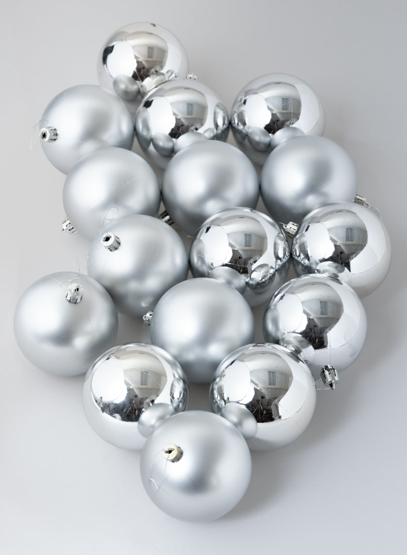A set of 3in round matte and shiny silver ornament balls arranged on a light gray surface.