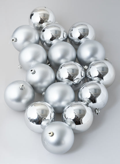 A set of 3in round matte and shiny silver ornament balls arranged on a light gray surface.