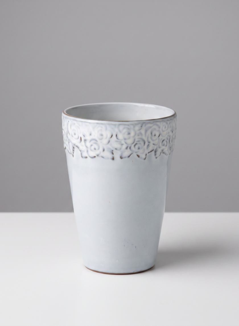 A set of four 6-inch tall Aurelie Rose Border cachepots, crafted from white ceramic and adorned with a delicate rose border along the rim, are displayed on a white surface against a light gray background.