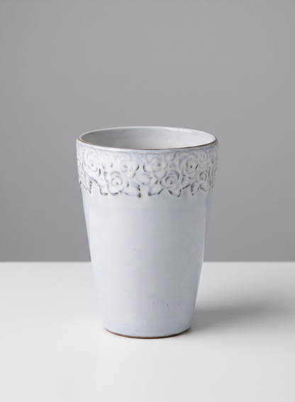 A set of four 6-inch tall Aurelie Rose Border cachepots, crafted from white ceramic and adorned with a delicate rose border along the rim, are displayed on a white surface against a light gray background.