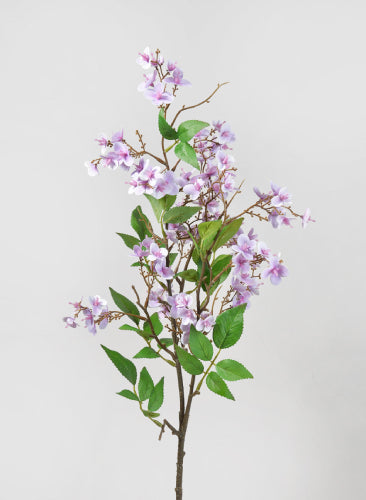 Artificial flower branch with purple flowers and green leaves on a light gray background