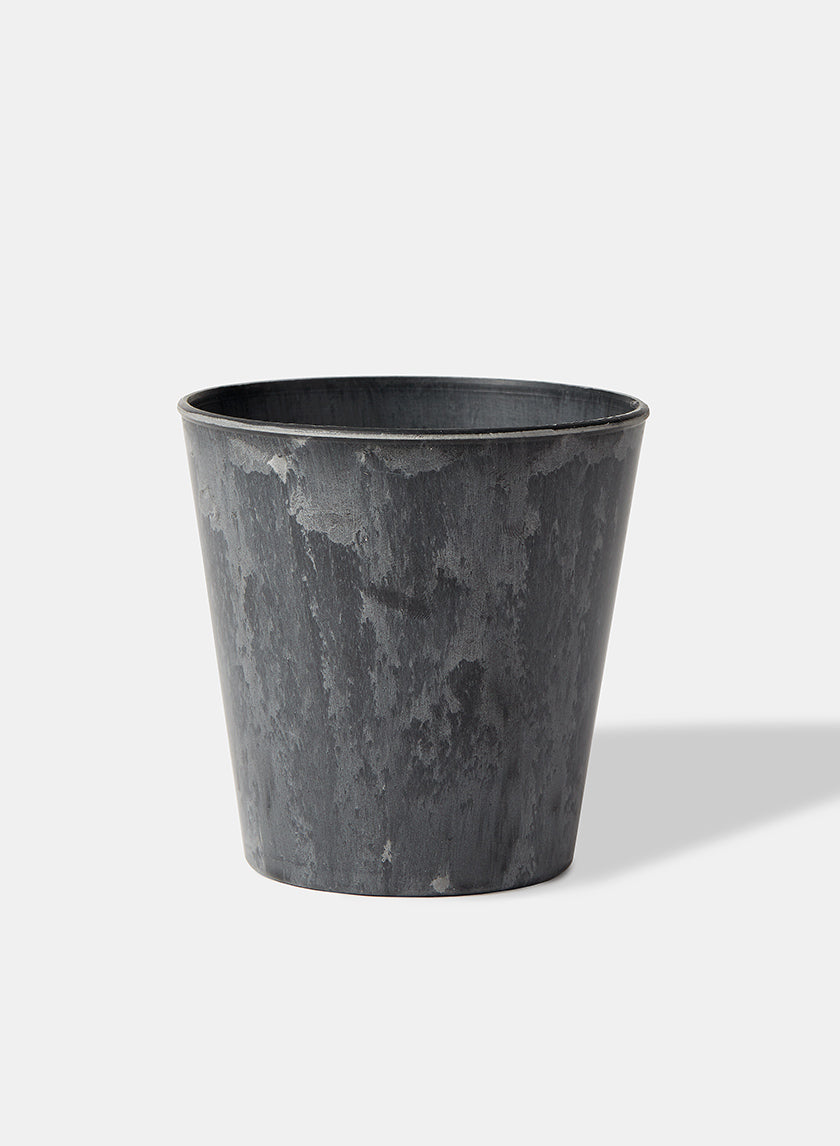 The Aged Black Flower Bucket, a dark gray cylindrical plant pot with an aged black finish and weathered texture, is centered on a white background, casting a soft right shadow. Ideal for industrial chic bucket-style floral arrangements.